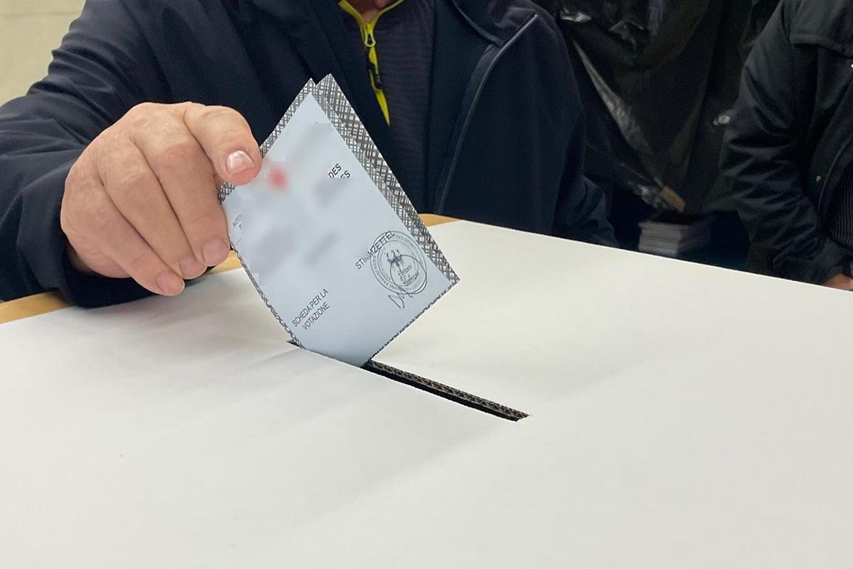 Un elettore infila la scheda elettorale nell'urna per votare